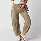 Front view of khaki barrel-leg high-waist jeans with curved seams, worn with a white t-shirt and woven bag