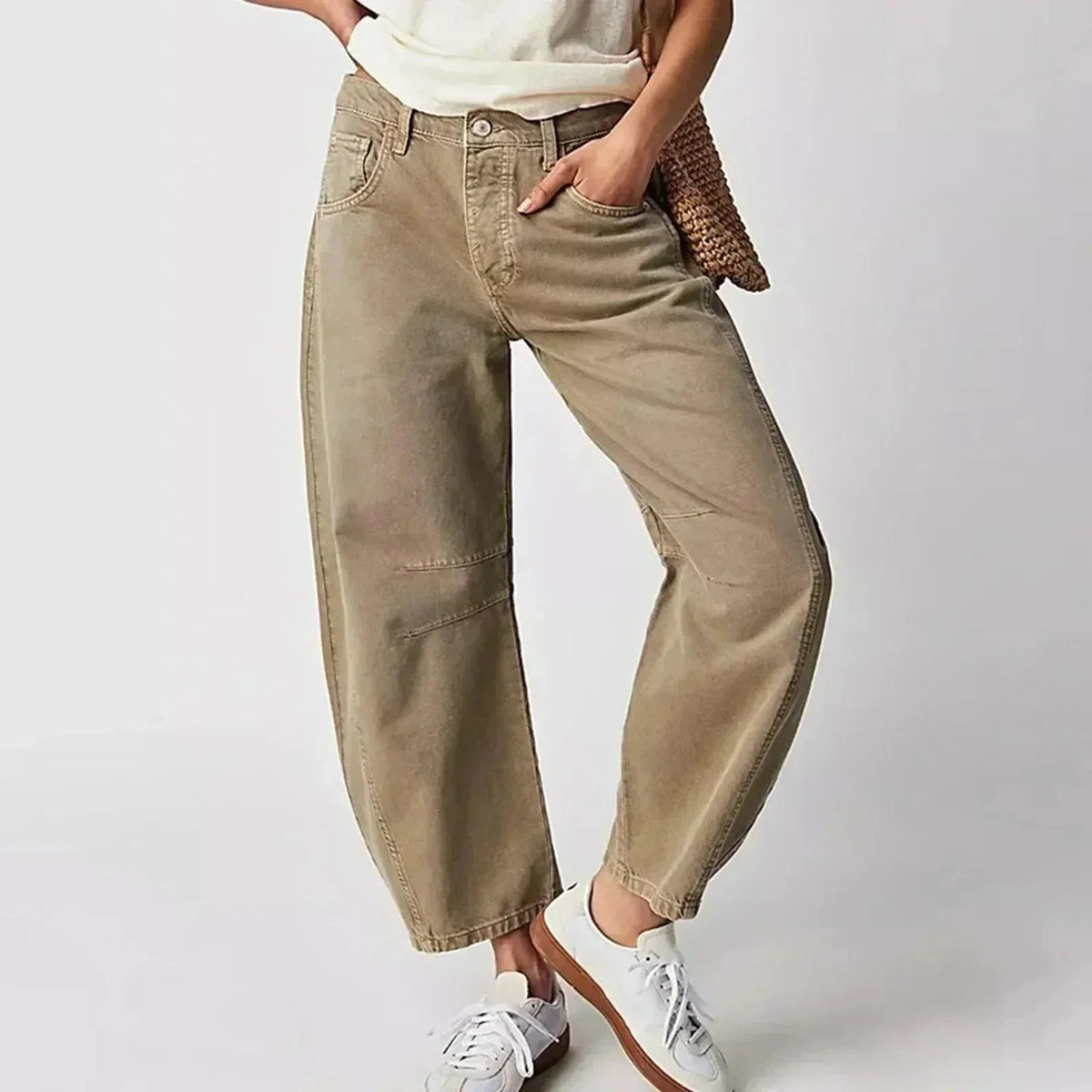 Front view of khaki barrel-leg high-waist jeans with curved seams, worn with a white t-shirt and woven bag