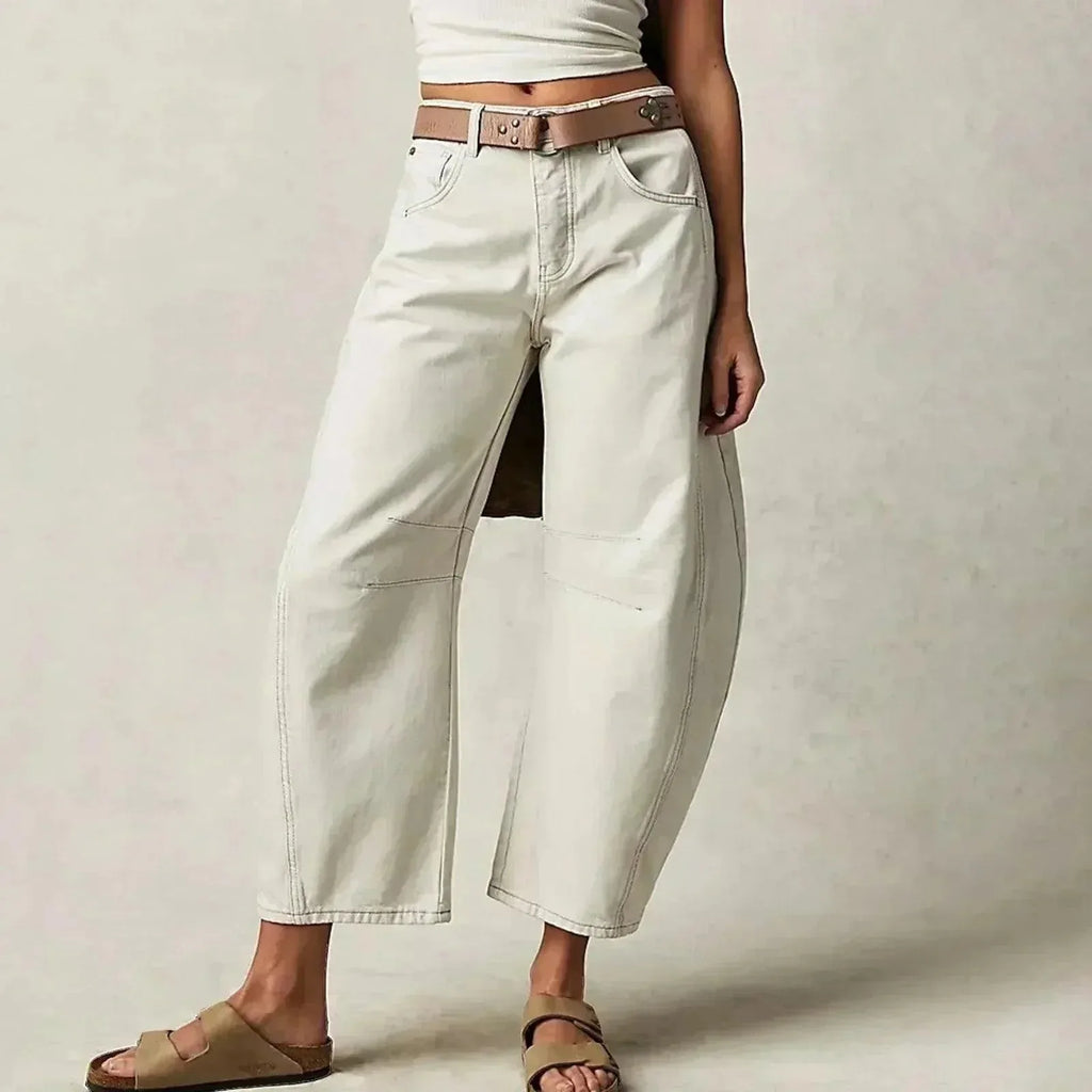 Off-white barrel-leg jeans styled with a brown leather belt and neutral slide sandals