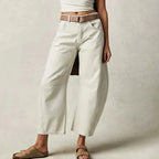 Off-white barrel-leg jeans styled with a brown leather belt and neutral slide sandals