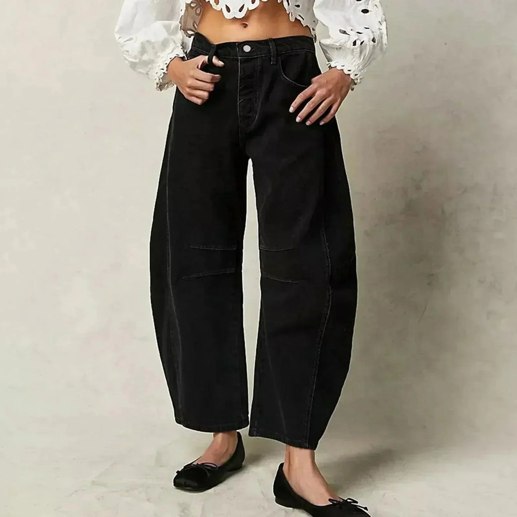 Black barrel-leg jeans worn with an embroidered white blouse and black bow-detail flats