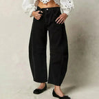 Black barrel-leg jeans worn with an embroidered white blouse and black bow-detail flats