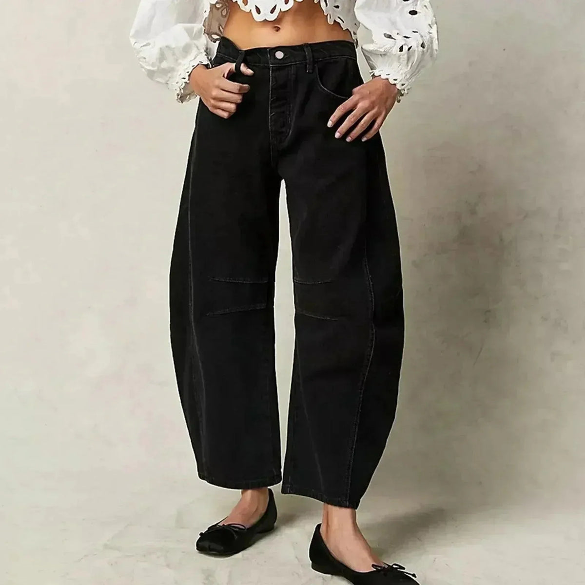 Black barrel-leg jeans worn with an embroidered white blouse and black bow-detail flats