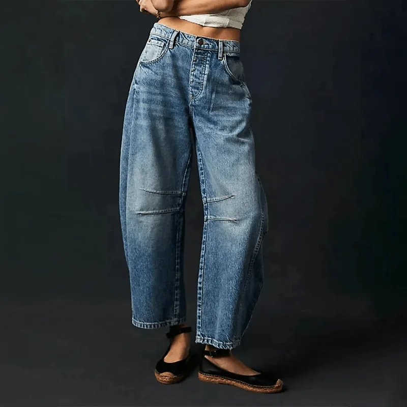 Light-wash blue denim barrel jeans paired with black espadrille flats against a dark backdrop