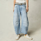 Faded light-wash barrel jeans styled with a woven belt and white trainers