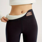 Close-up of fleece-lined black leggings waistband being pulled down to reveal soft cream brushed fleece interior