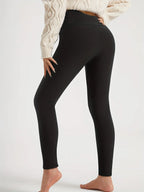 Side view of a woman wearing plain black high-waist fleece-lined leggings with a cropped cream jumper