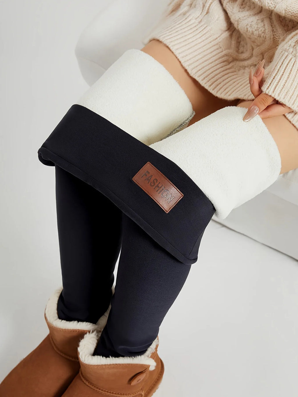 Close-up of black leggings ankle cuff folded down to show thick cream fleece lining, worn with tan shearling boots