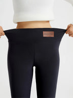 Close-up front view of black leggings waistband stretched wide, showing brown fabric patch labelled Fashion