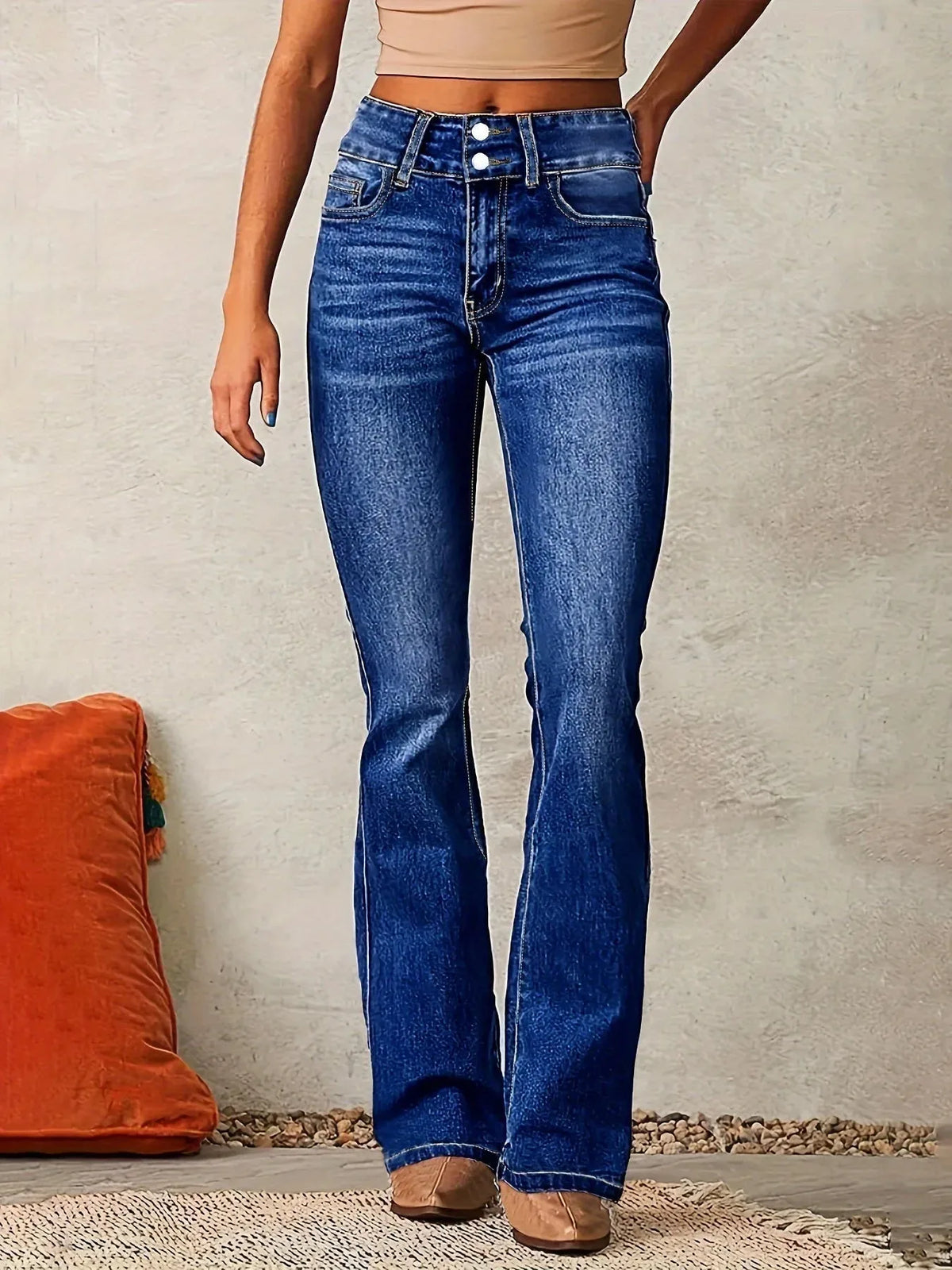 Close front view of mid-blue flared denim jeans highlighting raised topstitching and slim hip fit