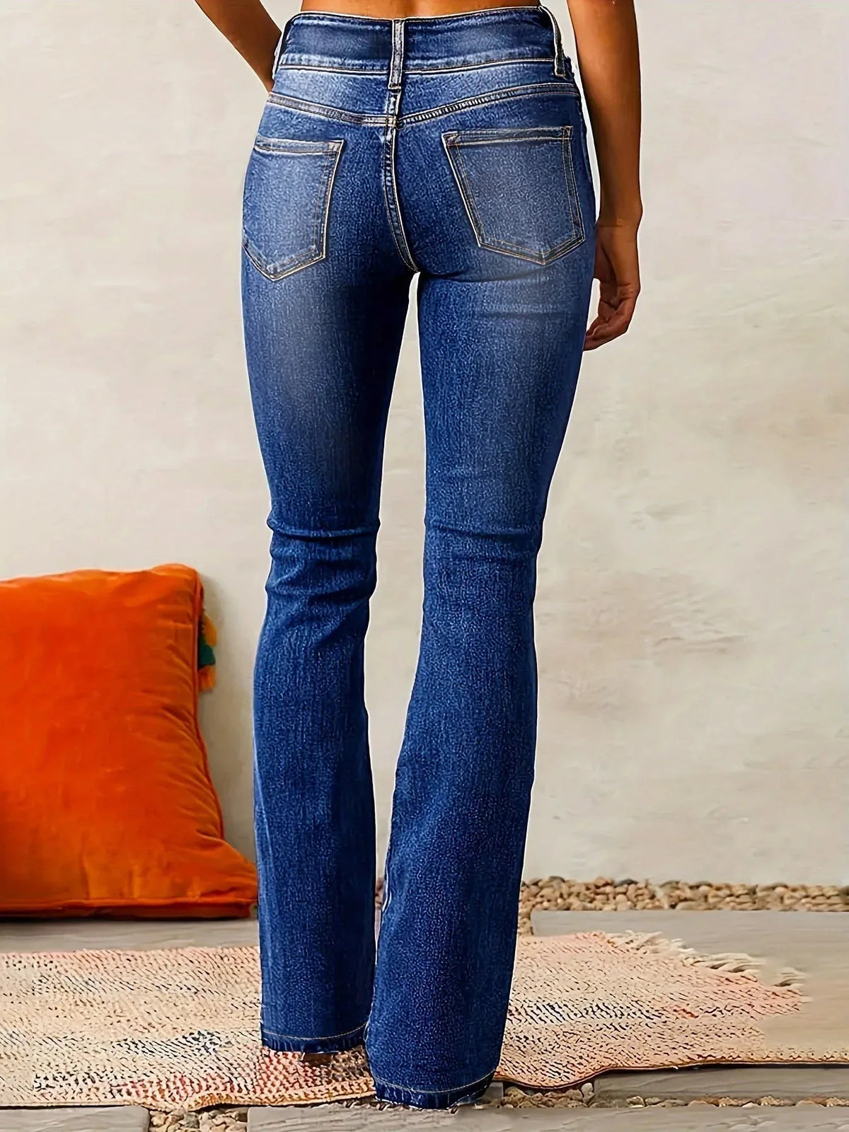 Rear view of dark blue flared jeans showing the leg silhouette flaring from knee to ankle