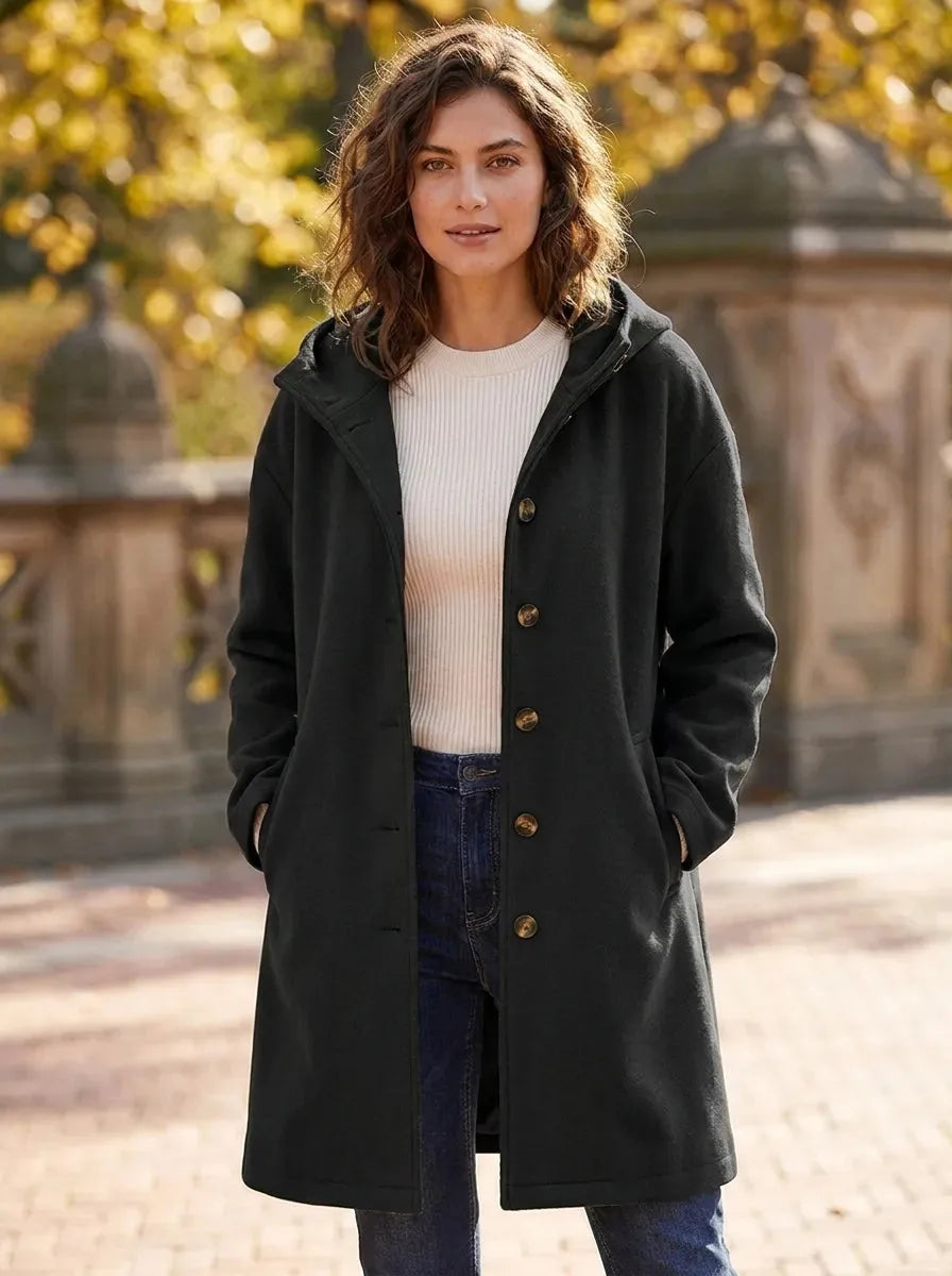 Model wearing the hooded longline coat in a deep forest green shade, fully buttoned up