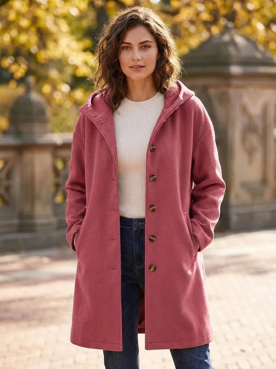 Model wearing the hooded longline coat in a dusty rose pink shade over a cream jumper