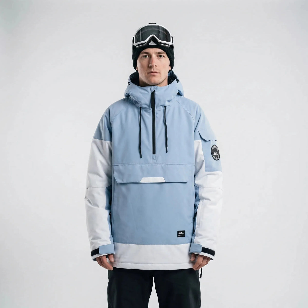 Model wearing the anorak in dusty blue and white colourblock with hood up and goggles on