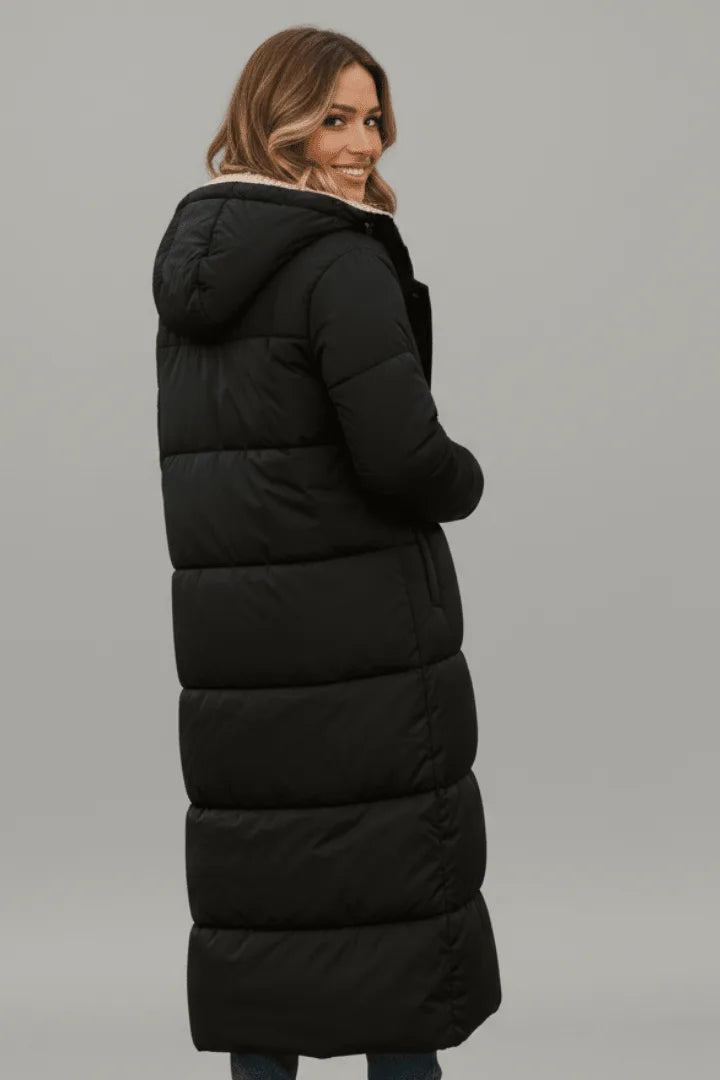 Back view of a woman in the black hooded puffer coat, highlighting the horizontal quilted panels and attached hood