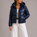 Close-up front view of the navy puffer jacket showing zip closure, hood snaps and quilted panels