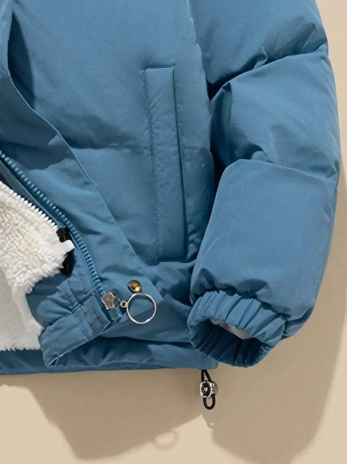 Close-up of pink puffer jacket zip pull and front pocket on model
