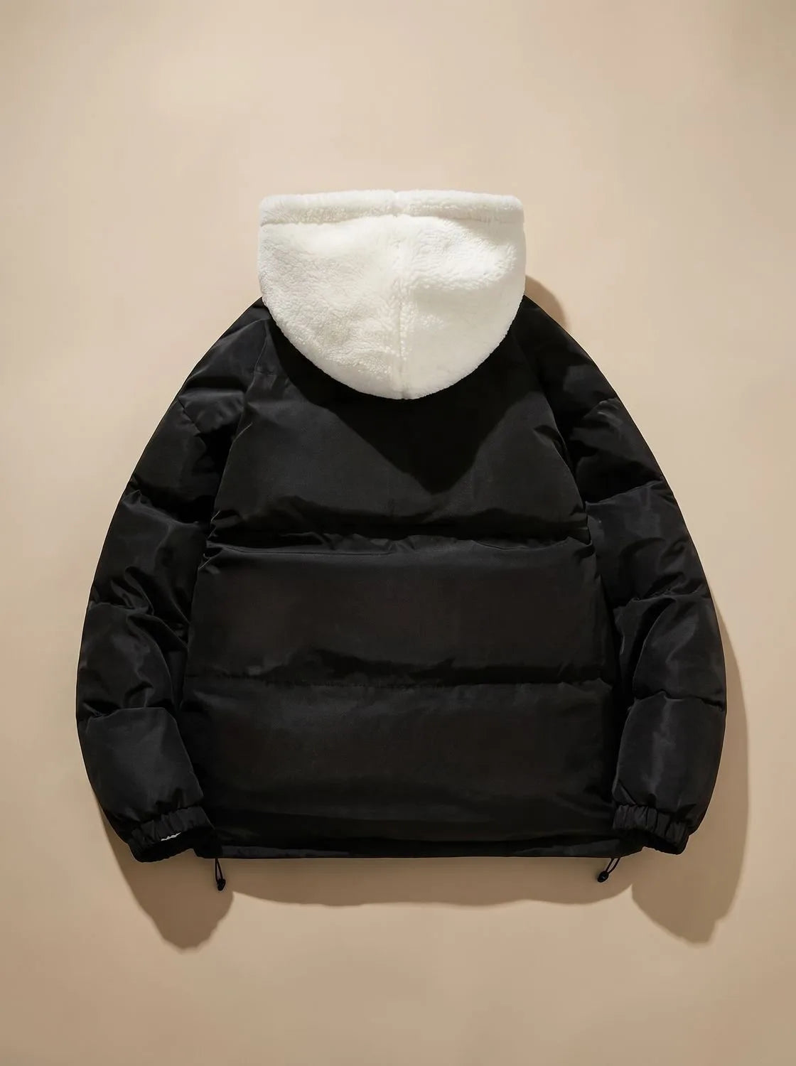 Back view of black puffer jacket showing quilted panels and cream sherpa fleece hood
