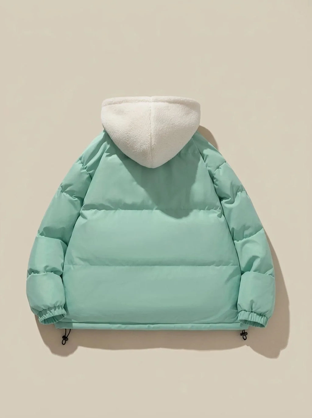 Full-length shot of model wearing pink puffer jacket with hood up outdoors
