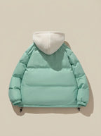 Full-length shot of model wearing pink puffer jacket with hood up outdoors