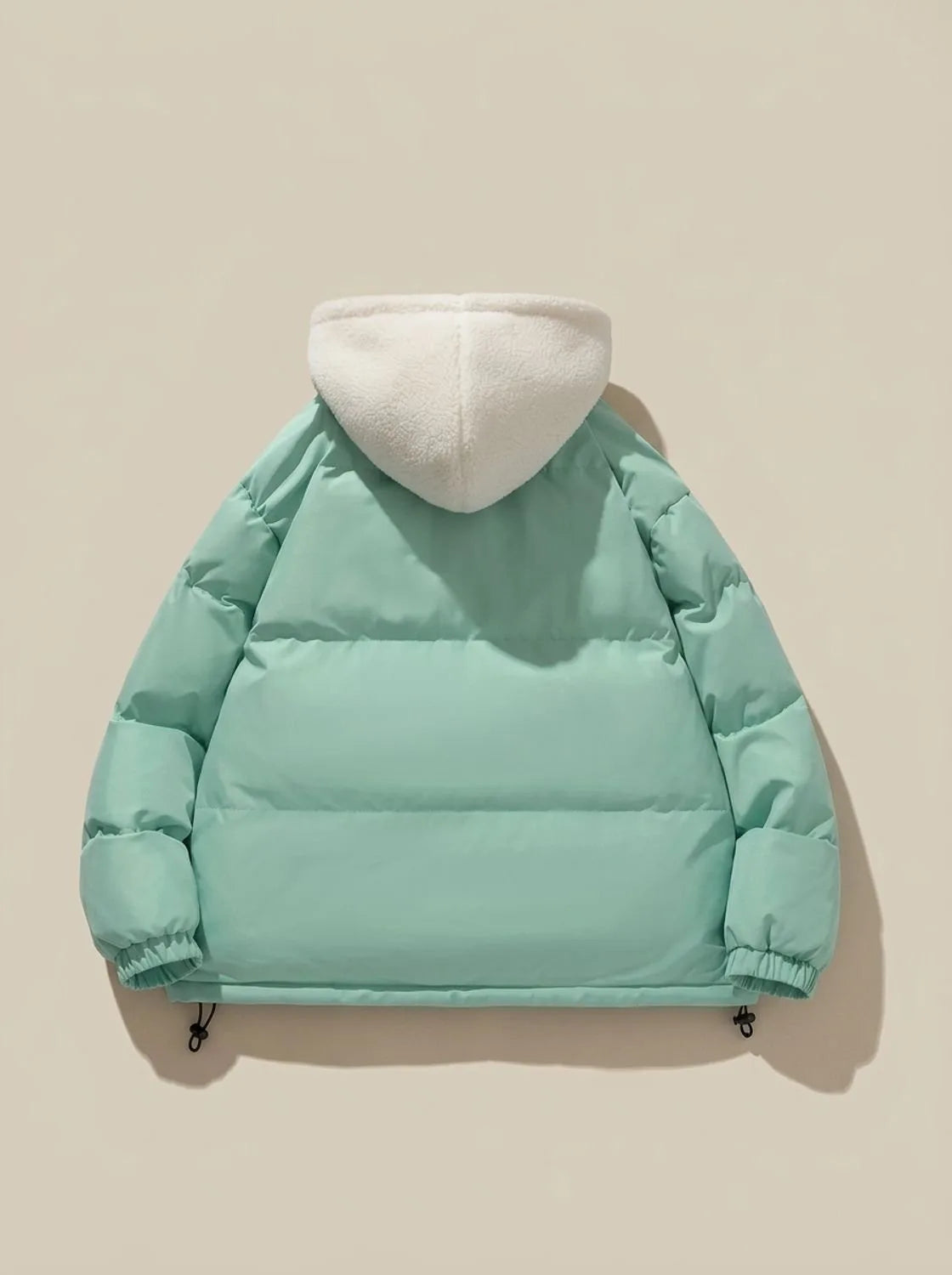 Full-length shot of model wearing pink puffer jacket with hood up outdoors