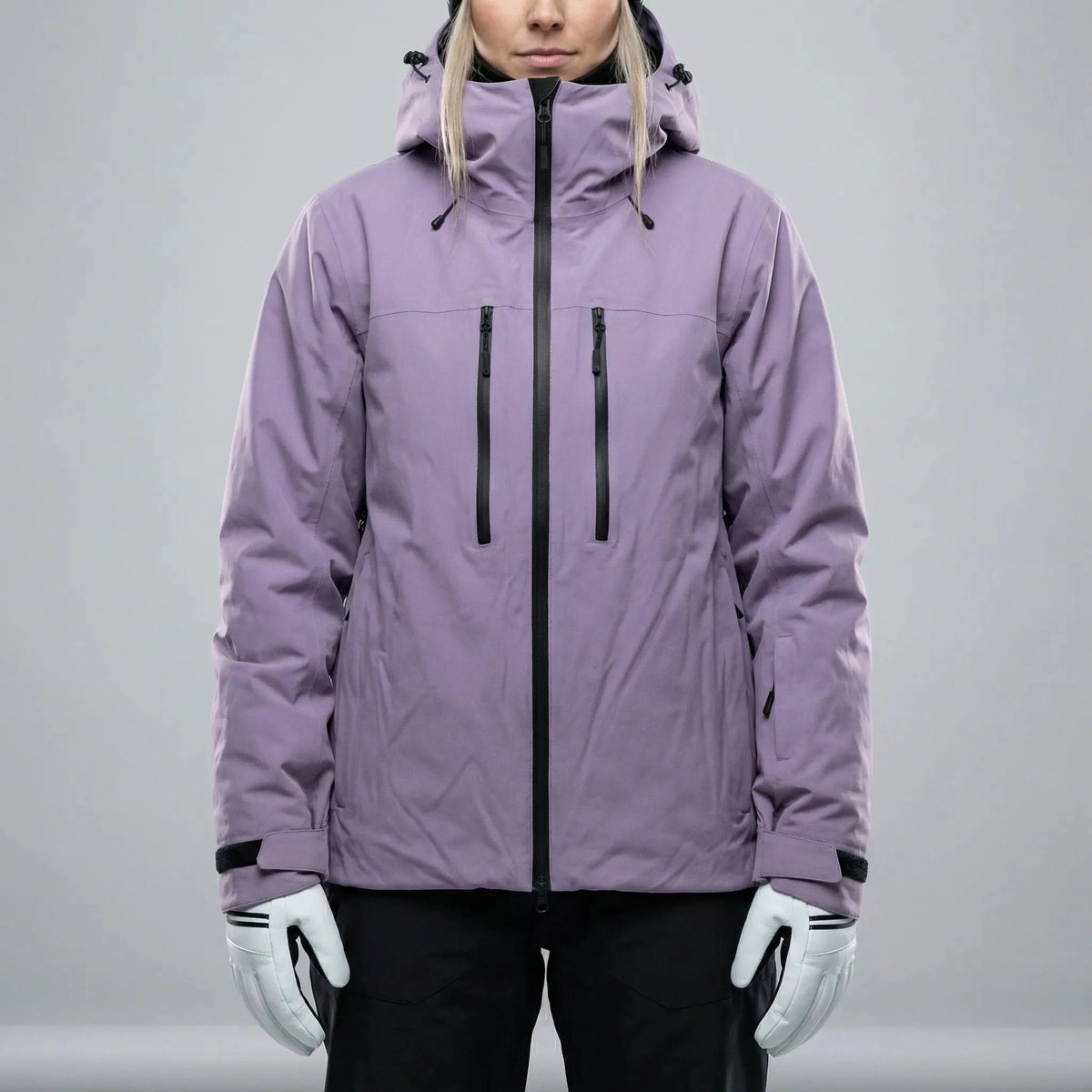 Front view of a lilac purple hooded ski jacket with black zip and twin chest pockets, worn over black ski trousers
