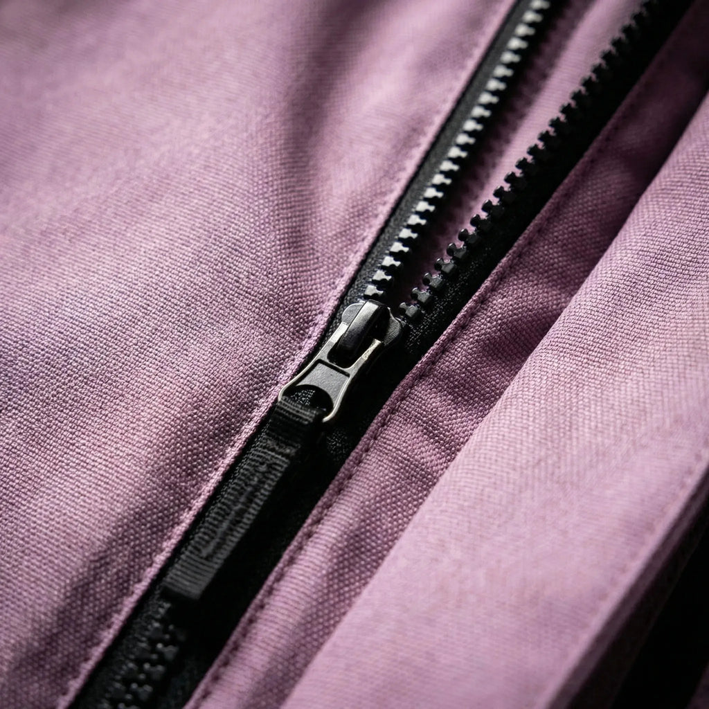 Close-up of the lilac fabric and matte black zip pull on the jacket's centre front closure