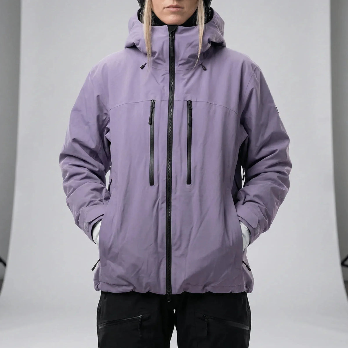 Model wearing the lilac hooded ski jacket fully zipped with hood up over a black beanie