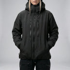 Front view of the same jacket style in black, hands in side pockets, worn over black ski trousers
