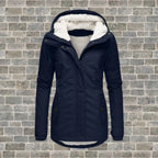 Navy blue hooded winter coat with sherpa fleece lining and zip front, shown flat against a brick wall