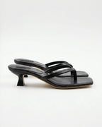 Side view of black leather kitten-heel sandal with square toe and thin crossover straps against a white background