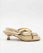 Gold metallic leather thong sandal with sculptural spool heel and square toe, side profile