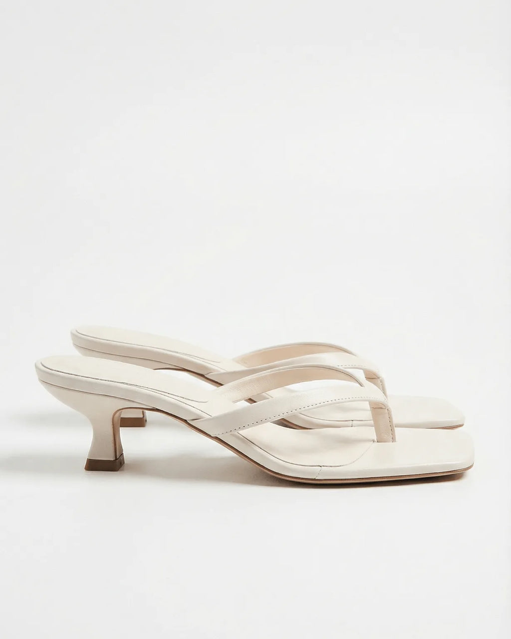 Ivory leather flip-flop style sandal with slim straps and flared spool heel, side angle