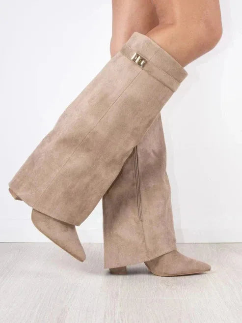 Side view of beige suede knee-high boots with foldover flap panel and pointed toe on model