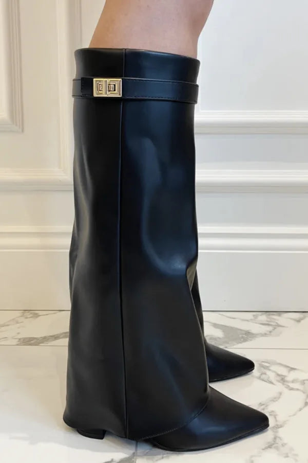 Side profile of black faux leather knee-high flap boots with pointed toe against marble floor