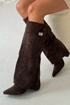 Close-up side view of black suede flap boots highlighting visible side zipper and cuff strap