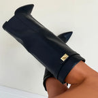 Close-up angled shot of black leather foldover boot cuff showing gold buckle and pointed toe silhouette