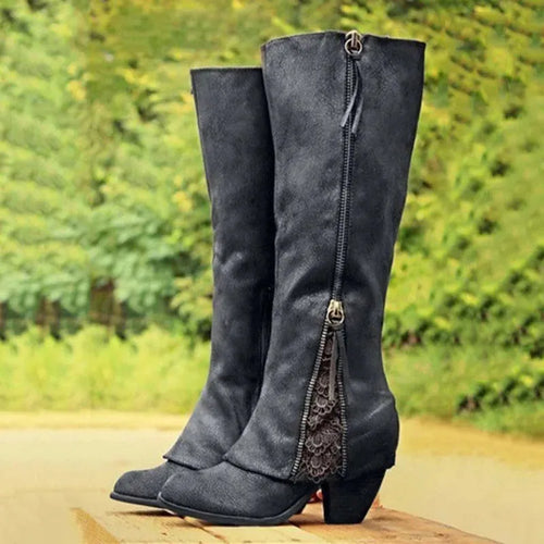 Black knee-high boots with front zip and tassel pull, showing floral lace insert above the block heel
