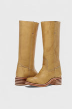 Angled front pair view of yellow leather knee-high boots showing the curved seam detail above the ankle