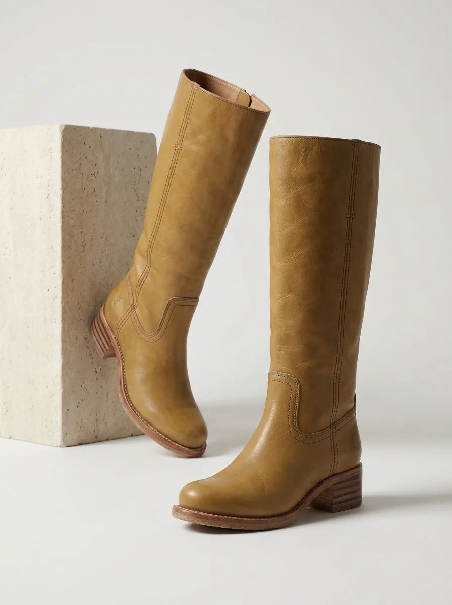 Woman seated wearing brown leather knee-high boots with black tights, close view of stacked heel