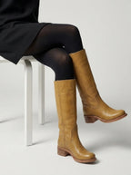 Woman walking in light tan leather knee-high boots, close-up of shaft and round toe shape