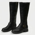 Black knee-high riding boots with visible side zip and ankle buckle strap, studio shot