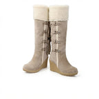 Front pair view of beige knee-high boots showing fold-down shearling cuffs and buckle straps