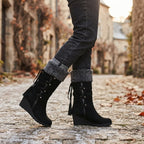 Close-up of model walking in black knee-high boots with folded grey cuff on cobbled street