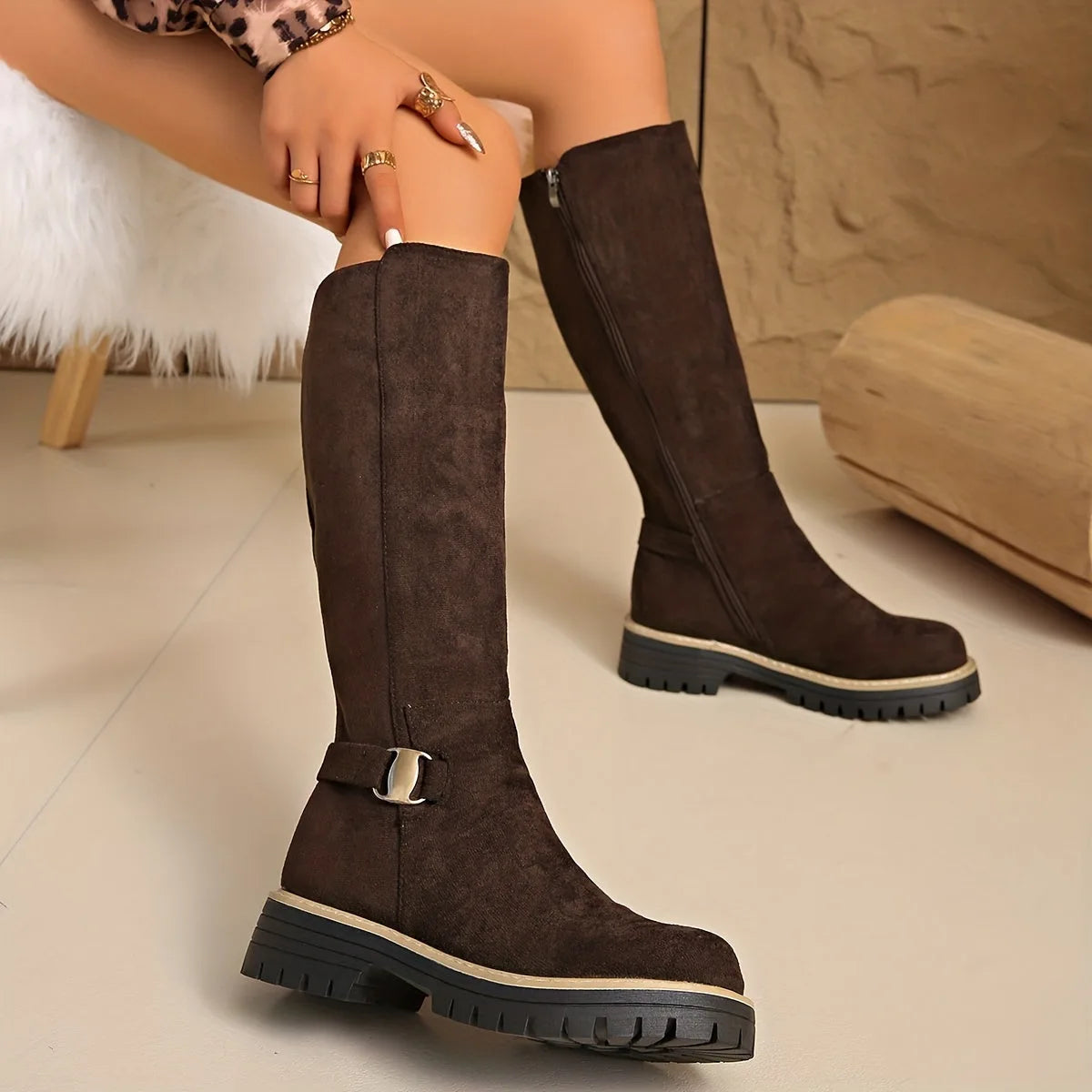 Dark brown suede knee-high boots with gold buckle hardware and lug sole, crossed leg pose