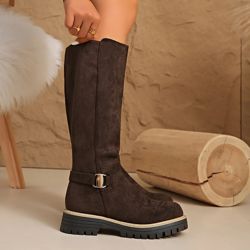 Close-up of coffee brown suede boot shaft with side zip, hand resting on the top edge