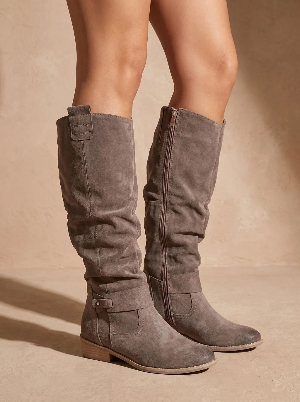 Grey suede knee-high slouch boots with side zip and pull tab, shown in profile against a neutral backdrop