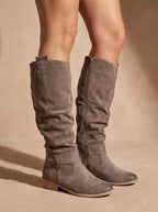 Grey suede knee-high slouch boots with side zip and pull tab, shown in profile against a neutral backdrop