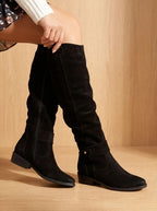 Black suede knee-high slouch boots with side zip, pull tab and buckle, worn with a floral chiffon dress