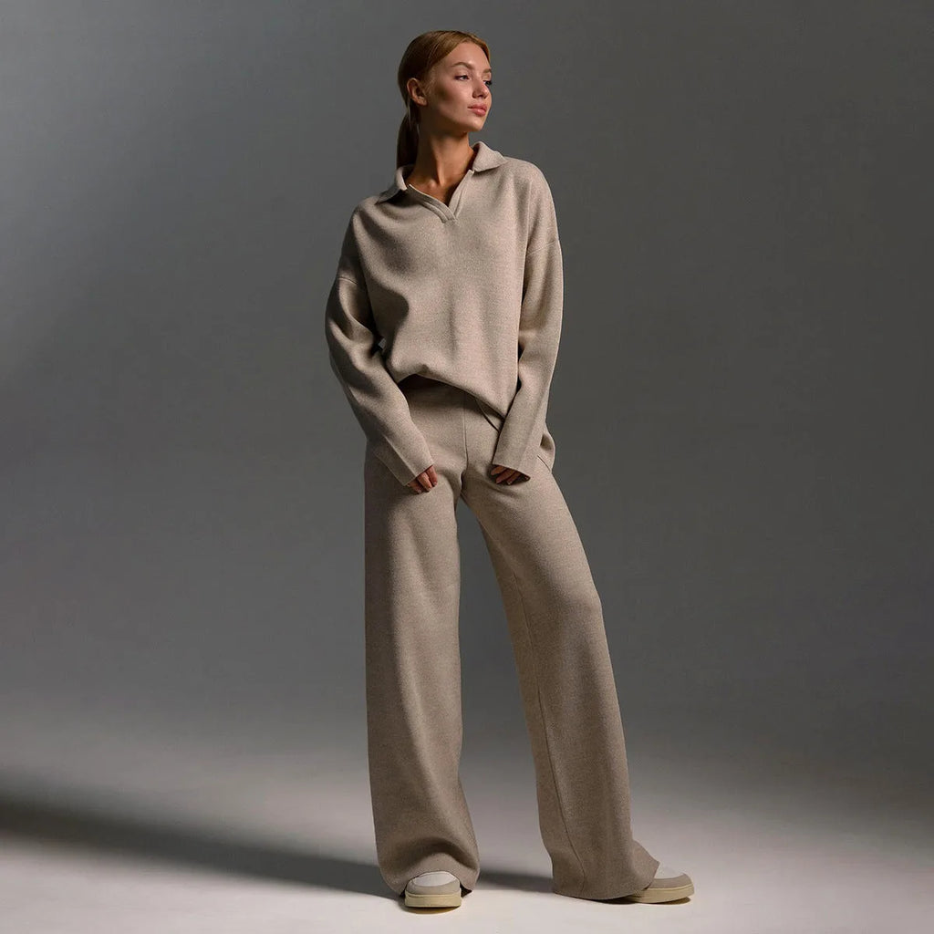 Detail of the wide leg knit trouser hem resting over grey and cream trainers